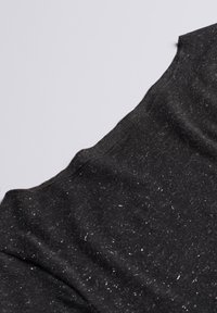 Sort T-shirt med en blød tekstur og sølvglimt, en rund halsudskæring og synlige syninger langs kanterne.