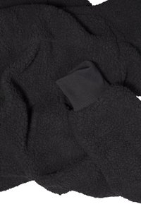 Tessuto in pile nero con una superficie testurizzata e una fettuccia a coste. Il materiale è morbido, peloso e stropicciato, mostrando una tonalità di nero intenso.