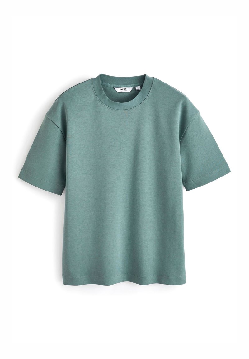 T-shirt vert uni à manches courtes et col rond, posé à plat avec une étiquette de col visible sur fond blanc.