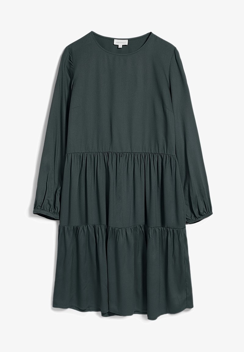 Tummanvihreä, pitkähihainen mekko, jossa on pyöreä pääntie, kerroksellinen muotoilu ja rypytetyt yksityiskohdat vyötäröllä ja hihoissa. Sileä kangastuntuma.