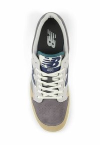 Grijze suède sneaker met lichtbeige accenten, witte veters en een marineblauw logo. Voorzien van een geperforeerde teen en een gevoerde binnenzool.