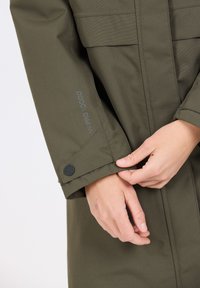 Olivgrön vattentät jacka med knappmanchetter, synliga sömdetaljer och "W-PRO 10000" tryckt på ärmen. Slät textur.