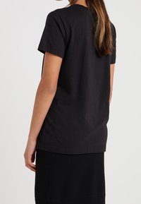 Svart bomull T-shirt med korta ärmar och rund halsringning. Har en avslappnad passform och en slät yta. Inga synliga mönster eller dekorationer.