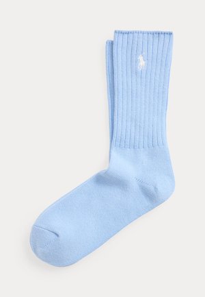 Calzino di cotone azzurro chiaro a coste con logo ricamato di un giocatore di polo bianco vicino al polsino, mostrato disteso su uno sfondo bianco.