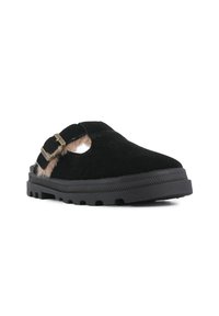 Chaussure à enfiler en daim noir avec un accent en fourrure, dotée d'un bout arrondi et d'une semelle en caoutchouc noir texturé. Détail de boucle réglable sur le côté.