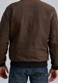 Giacca bomber in pelle marrone con polsini e orlo a coste, caratterizzata da una texture liscia e un design minimalista. La vista dal retro mostra le cuciture delle spalle.