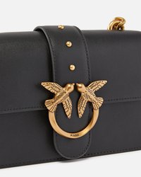 Borsa a mano in pelle nera con chiusura a tema uccello in tonalità oro, finitura testurizzata, borchie decorative e accento metallico circolare.