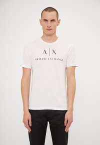 Hvit bomulls T-skjorte med rund hals og korte ermer, med en stor svart grafikk av "A|X ARMANI EXCHANGE" trykt på forsiden.