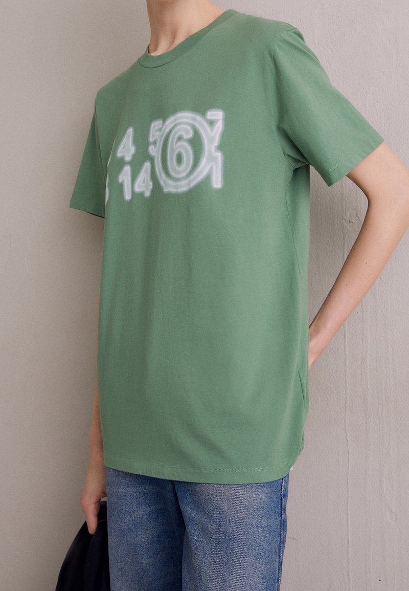 Groene katoenen T-shirt met een witte graphic met de cijfers 4, 5, 6, 1 en 14, ronde ontwerpaccenten en korte mouwen.
