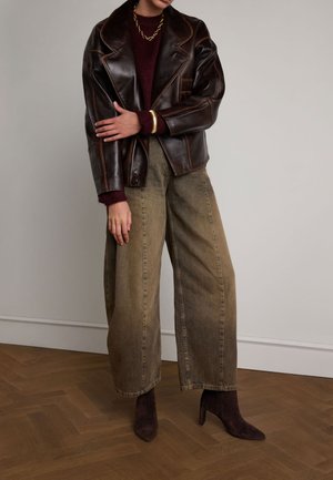 Bruine leren dubbelbreasted jas met contrasterende stiksels, bordeauxkleurige trui, beige wijde broek en bruine suède enkellaarsjes.