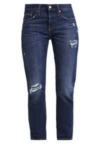Jeans in denim blu scuro con dettagli strappati, ginocchia strappate, cinque tasche, chiusura con bottone e passanti per cintura.