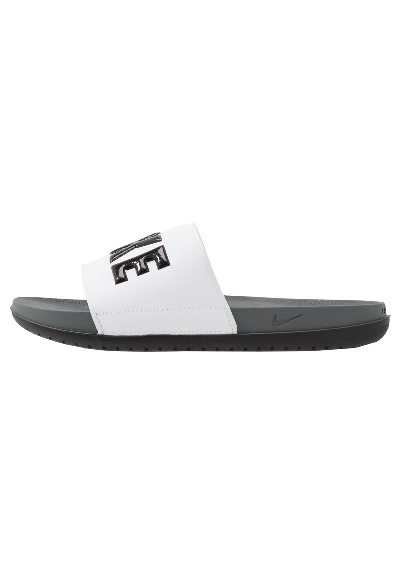 Nike šlepetės su baltu sintetiniu dirželiu, kuriame yra iškilęs juodas logotipas. Tamsiai pilka paminkštinta padas su tekstūruoto paviršiaus, užtikrinančiu sukibimą.