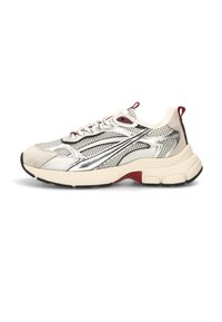 Zapatillas con parte superior de malla y gamuza en beige claro, detalles plateados, media suela blanca gruesa, acentos rojos y suela de goma negra.