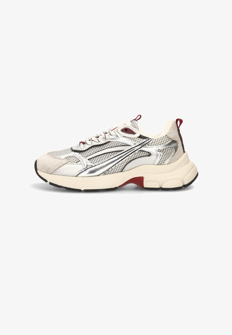 Zapatillas con parte superior de malla y gamuza en beige claro, detalles plateados, media suela blanca gruesa, acentos rojos y suela de goma negra.