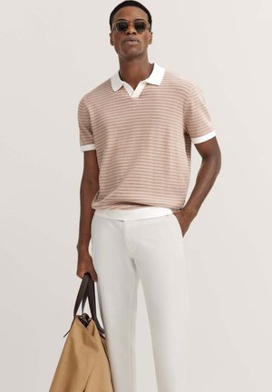 Kurzarm-Polohemd mit gestreiftem Muster in Hellbraun, dazu weißer Kragen und Bündchen, kombiniert mit maßgeschneiderten weißen Hosen und einer braunen Tasche.