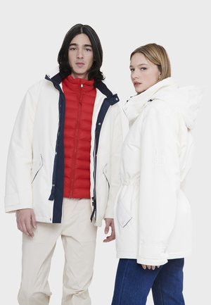 Giacche bianche con accenti blu navy e gilet imbottiti rossi aderenti sotto. Caratteristiche: cappucci regolabili e cinture elastiche in vita; tessuto testurizzato.