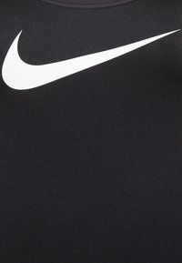 Zwarte sporttop gemaakt van glad, rekbaar materiaal met een opvallend wit Nike swoosh-logo op de borst.