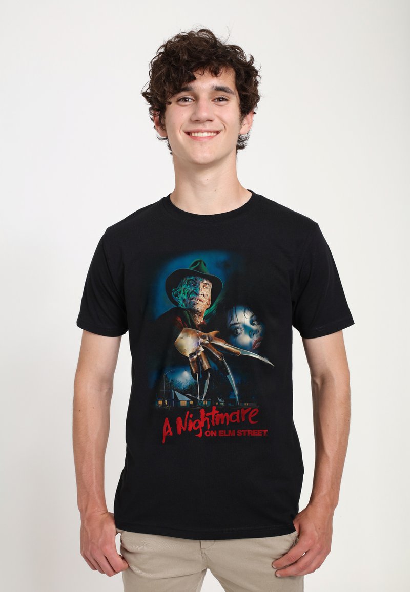 Schwarzes T-Shirt mit einem Grafikdesign zu "A Nightmare on Elm Street". Das Design zeigt eine bedrohliche Gestalt mit Klauen und ein verzweifeltes Gesicht im Hintergrund.