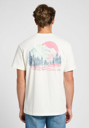 Short-sleeved cream t-shirt featuring a colorful mountain and forest graphic on the back, with a large pink sun and brand name "LEE."
