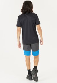 Kortärmad svart träningsskjorta med grå och blå shorts, med en färgblocket design. Bärs med svarta vandringsskor.