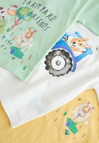 Trzy bawełniane koszulki: jasny zielony z wiejskimi zwierzętami, biały z niebieskim traktorem oraz żółty z owcą. Różnorodne zabawne grafiki i kolory.