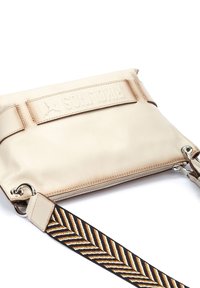 Beige lædertaske med lynlås, der har en tekstureret rem med et chevronmønster i brun, creme og sort. Fronten har et præget logo.