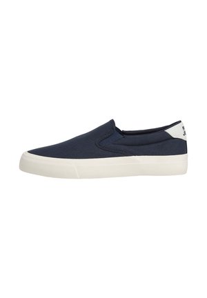 Marineblaue Slip-On-Sneaker mit weißer Gummisohle und weißem Fersenlasche, von der Seite auf weißem Hintergrund gesehen.