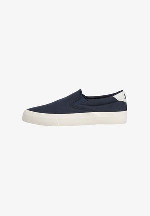 Sneaker blu navy slip-on con suola in gomma bianca e linguetta bianca sul tallone, vista laterale su sfondo bianco.