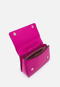 Piccola borsa a tracolla di colore rosa brillante con il flap aperto, che mostra il vano interno e le chiusure a pulsante su uno sfondo bianco.
