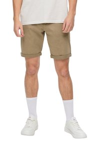 Khaki-Shorts mit umgeschlagenen Bündchen, aus einem glatten Baumwollgemisch gefertigt. Kombiniert mit weißen Kniestrümpfen und weißen Sportschuhen.