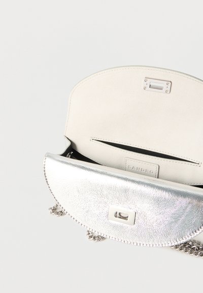 Ασημένια μεταλλική τσάντα σε σχήμα μισοφέγγαρου με λουράκι αλυσίδας, ανοιχτό καπάκι που αποκαλύπτει εσωτερική τσέπη και ετικέτα με το λογότυπο της Sandro στο εσωτερικό.