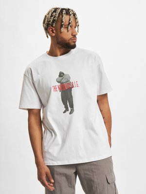 Hvid bomulds-T-shirt med grafisk tryk af en person i mørkt tøj med teksten "THE NOTORIOUS B.I.G." i rødt. Korte ærmer, afslappet pasform.