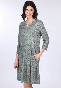 Blumenkleid aus grü fabric mit V-Ausschnitt, dreiviertel Ärmeln und gerafftem Bund. Verfügt über eine Tasche und einen gestuften Rock.