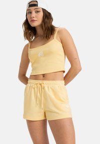 Geel geribbeld crop-top met een witte graphic, gecombineerd met bijpassende gele shorts met een elastische tailleband en een accent trekkoord.