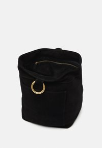 Sac en daim noir avec quincaillerie dorée, détail en anneau circulaire et poche zippée intérieure. Texture douce et forme structurée. Design ouvert.