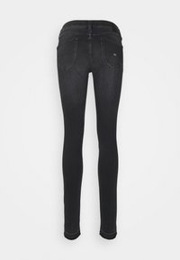 Jeans negros ajustados con una textura suave, diseño de cinco bolsillos y una cinturilla ligeramente contorneada. Cuenta con costuras estándar y dobladillos cerrados.