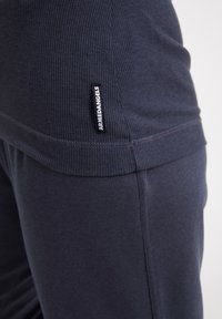 Top en tissu côtelé bleu marine avec un ourlet lisse, orné d'une étiquette noire portant le label "ARMEDANGELS". Design ajusté avec une texture subtile.