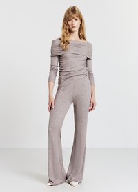 Tuta in tessuto grigio chiaro a coste con design scollato sulle spalle, maniche lunghe e pantaloni a gamba larga con bordi sfrangiati.