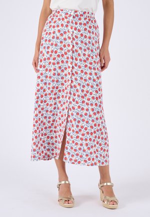 Weißer Midirock mit Knopfleiste vorne und rotem Blumenmuster, getragen mit goldfarbenen Keilsandalen und weißem Oberteil, dargestellt von der Taille bis zu den Füßen.