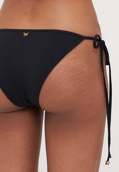 Black bikini bottom with adjustable side ties. Features a small gold butterfly accent on the back. Smooth texture, minimal coverage design.