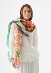 Écharpe colorée à motifs en tissu léger, présentant des motifs floraux et géométriques dans des tons d'orange, de jaune, de vert et de marron.