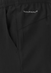 Svarta idrottsshorts med elastisk midja, med en slät textur och en liten "ENDURANCE"-logotyp på sidan.
