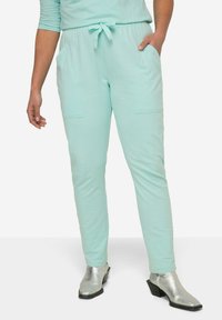 Pantalones jogger en un azul claro confeccionados en tela suave, con un diseño ajustado, cinturilla elástica con un lazo, y dos bolsillos frontales.