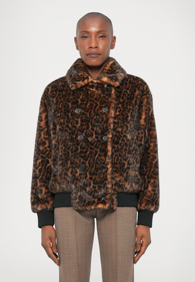 Casaco de pêlo sintético com estampa de leopardo, colarinho largo, design de botões duplos e punhos canelados pretos. O modelo usa calças ajustadas, xadrez.
