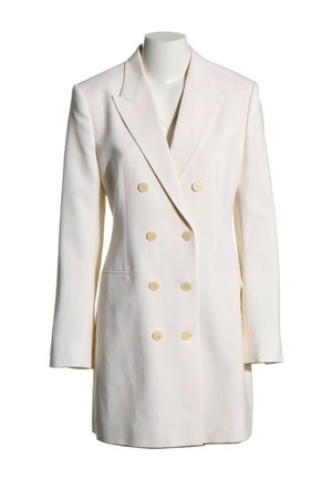 Blazer blanco de doble botonadura con seis botones beige, solapas con muesca, mangas largas y dos bolsillos delanteros en un maniquí sin cabeza.