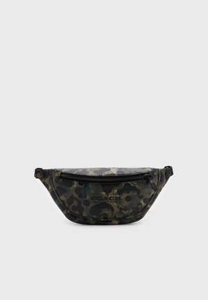 Sac banane Coach à motif camouflage avec fermeture éclair noire et sangles latérales ajustables sur un fond uni clair.