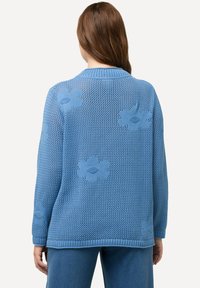 Blaue Strickjacke mit lockerer Passform, strukturiertem offenen Gewebe und floralen Mustern auf dem Rücken. Rippkragen und -ärmeln.