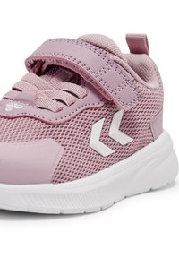 Rosa Netz-Sportschuh mit einer strukturierten Oberseite, verstellbarem Klettverschlussriemen und weißer Gummisohle. Verfügt über zwei weiße Chevron-Akzente.