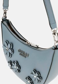 Borsa a tracolla in pelle blu con applicazioni floreali, hardware in argento e chiusura con zip. Presenta il logo del marchio e strass decorativi.