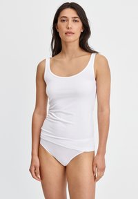 Witte tanktop met een ronde halslijn en dunne bandjes, gecombineerd met witte onderbroeken. Zacht katoenen materiaal met een gladde textuur.